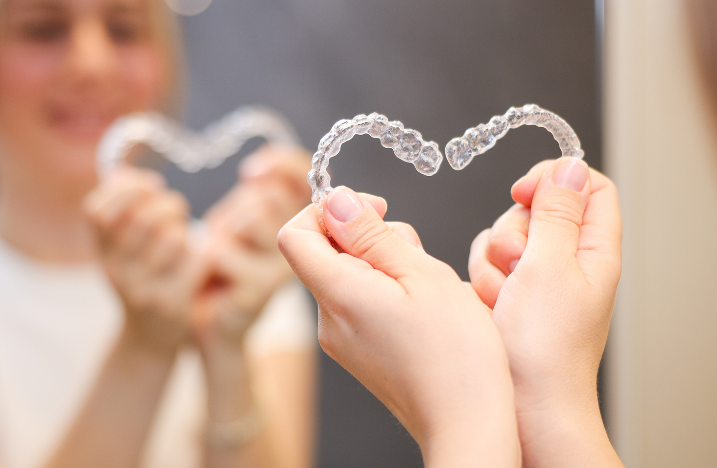 Young women is putting on clear dental aligner in the bathroom